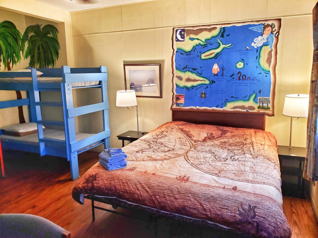 The map room, room 9, showing one bunk bed and the king bed, with a map mural.