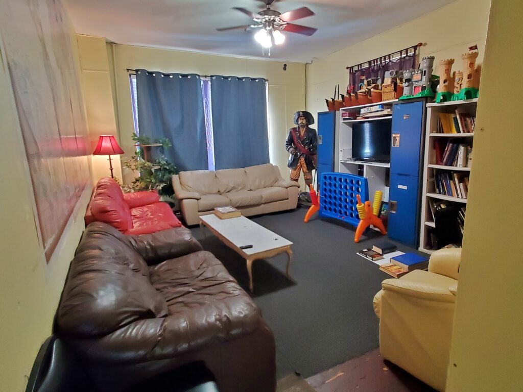 common room showing couches, toys, books, and tv