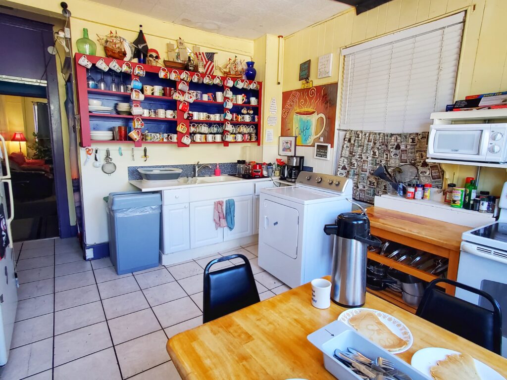 pirate haus kitchen showing the table, dryer, countertops, sink and drying area, and shelves full of mugs